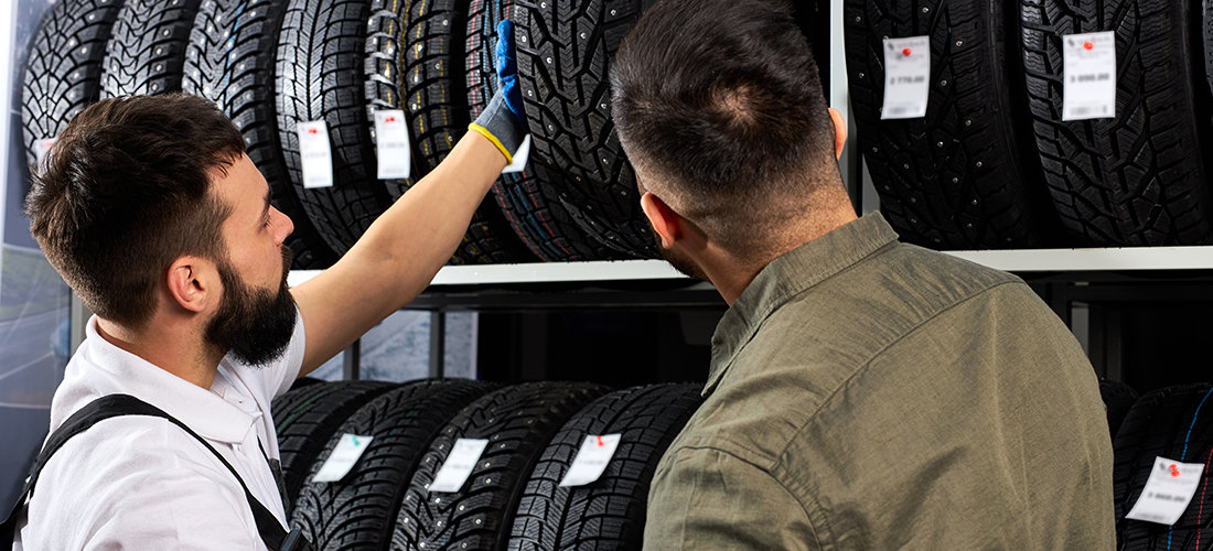 Empleado de un taller indicando los tipos de neumáticos al cliente de un taller